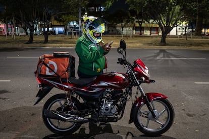 Repartidora por aplicación revisando su ruta para entrega de pedidos.