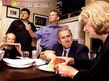 George W. Bush come pizza con los compañeros y la mujer y la hija de uno de los bomberos desaparecidos.