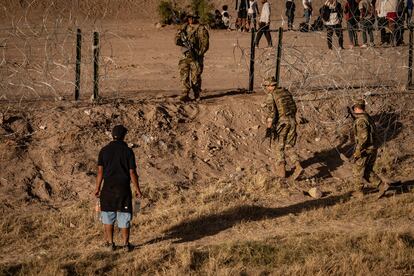 El Gobierno estadounidense ha enviado a la frontera a 1.500 soldados que se unen a los 3.500 que ya patrullaban el borde, para contener la llegada de miles de migrantes. En la imagen, un migrante observa a soldados estadounidenses cruzar un cerco de alambre, en el cerco entre Ciudad Juárez y El Paso. 