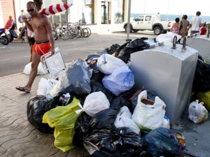 Un veraneante pasa por un calle de Rota donde se acumula basura.