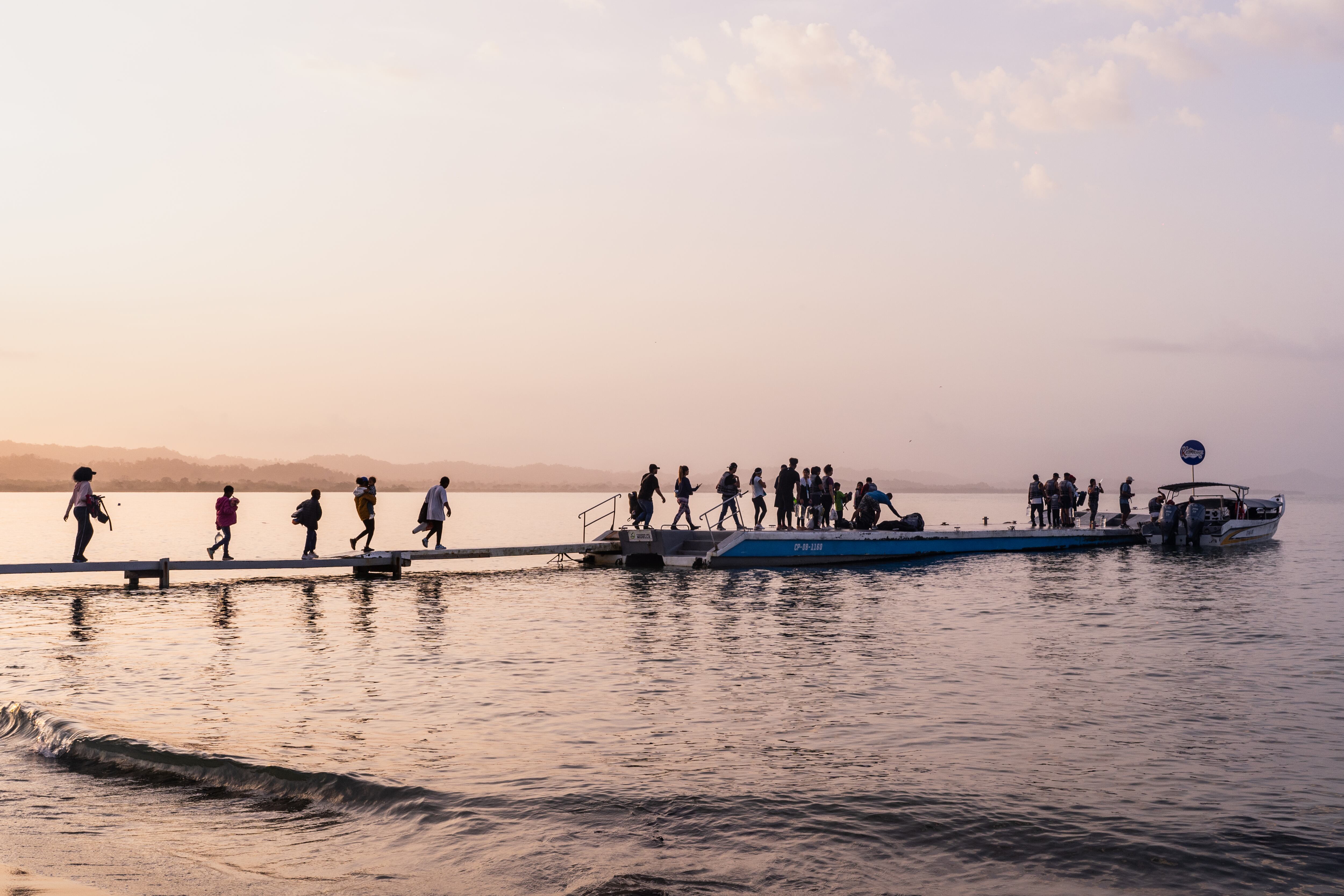 Migrantes caminan por uno de los muelles hacia la lancha que los llevará a selva del Darién para seguir la ruta a Estados Unidos, en Necoclí (Colombia), el 1 de marzo de 2024.