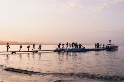 Varios migrantes caminan por uno de los muelles para embarcarse en la lancha que los llevará a la selva del Darién para seguir la ruta hacia Estados Unidos, en Necoclí, el 1 de marzo de 2024.