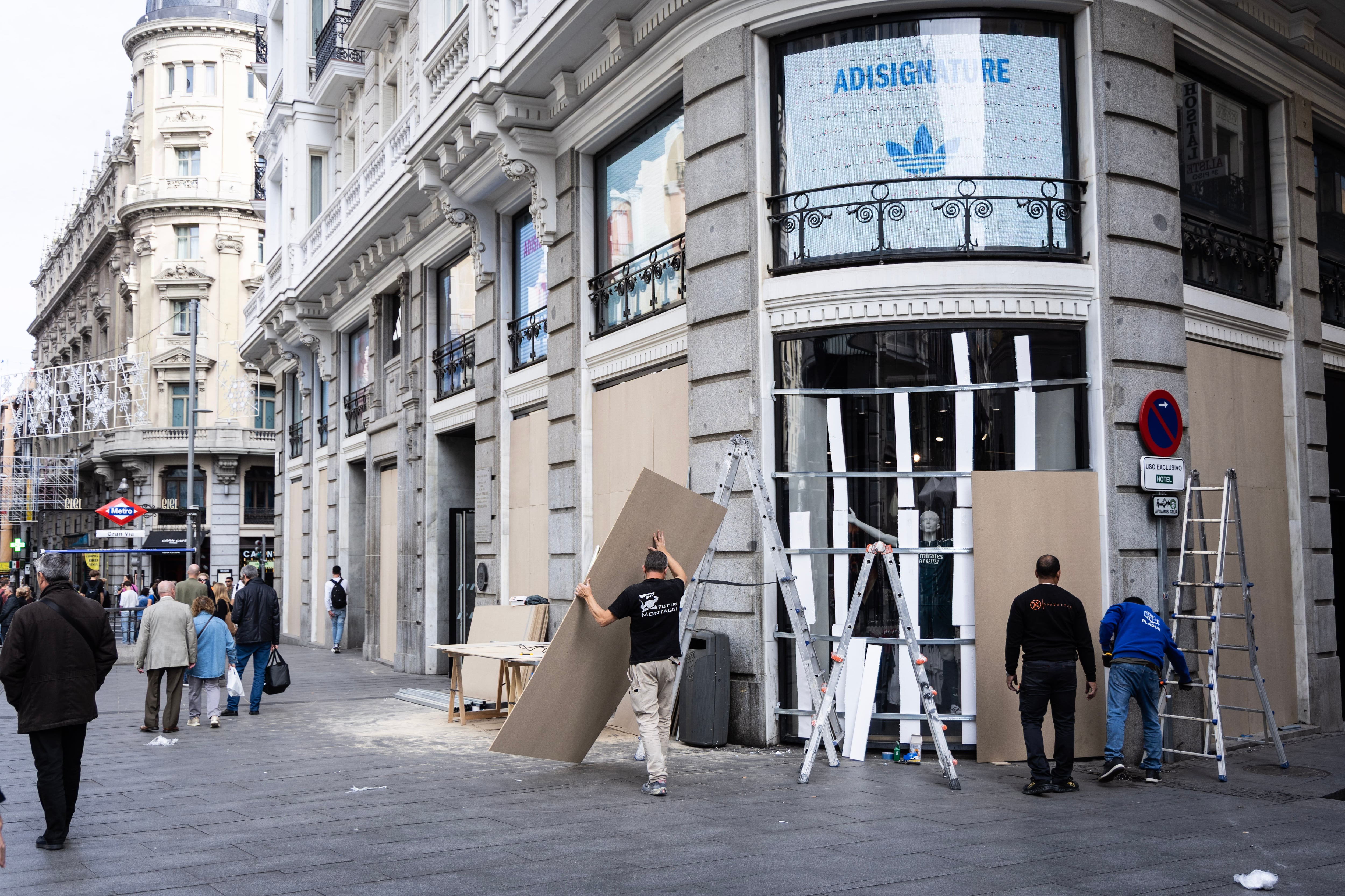 Operarios colocan tablones de madera en el escaparate de un comercio de la Calle Montera de Madrid.