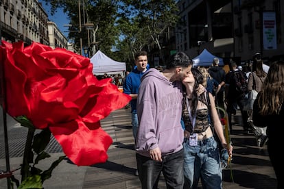 Una pareja de jóvenes se besa por las calles de Barcelona durante el día de Sant Jordi.