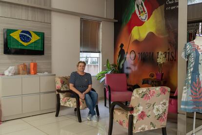 Merchant Ivette Izabel Kruger – a fervent Bolsonaro supporter – poses inside her shop in Quatro Pontes on Thursday, October 6, 2022. Behind her, a poster displays a message in favor of Brazil’s south seeking sovereignty from the rest of the country.