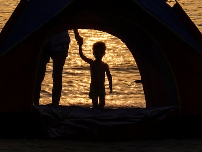 Una persona sostiene a un menor de la mano durante un atardecer en Dubái.