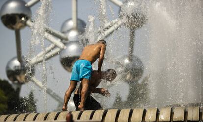 Dos hombres se refrescan en una fuente de Bruselas, cerca del Atomium, este miércoles.