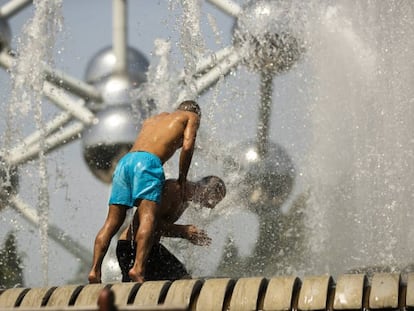 Dos hombres se refrescan en una fuente de Bruselas, cerca del Atomium, este miércoles.