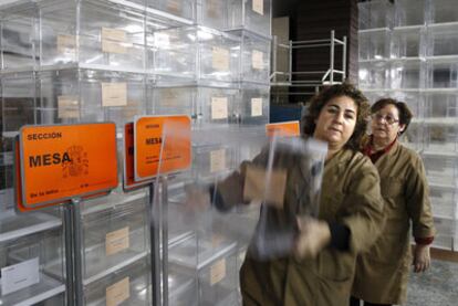 Dos trabajadoras de un almacén electoral en Sevilla preparan las urnas para la votación de hoy.