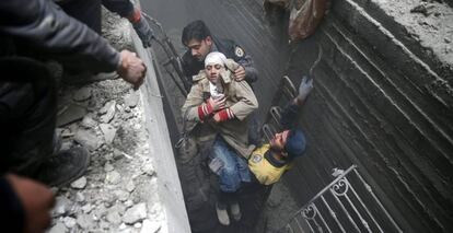 Miembros de la Defensa Civil Siria rescatan a una mujer tras un bombardeo en Duma.