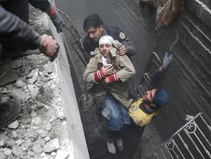 Miembros de la Defensa Civil Siria rescatan a una mujer tras un bombardeo en Duma.