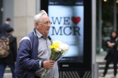 Un hombre lleva un tributo floral frente al cartel 'amamos Mánchester', colocado alrededor de toda la ciudad.