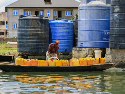 Una anciana llena bidones con agua en la comunidad de Agboyi, en Lagos, Nigeria.