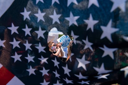 A través de un agujero en una bandera estadounidense, se observa a activistas que sostienen un letrero que lee "Mantengan legal el aborto", el 25 de junio de 2022, en Washington D. C. (EE.UU.).