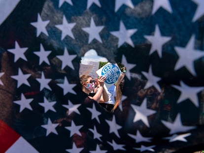 A través de un agujero en una bandera estadounidense, se observa a activistas que sostienen un letrero que lee "Mantengan legal el aborto", el 25 de junio de 2022, en Washington D. C. (EE.UU.).