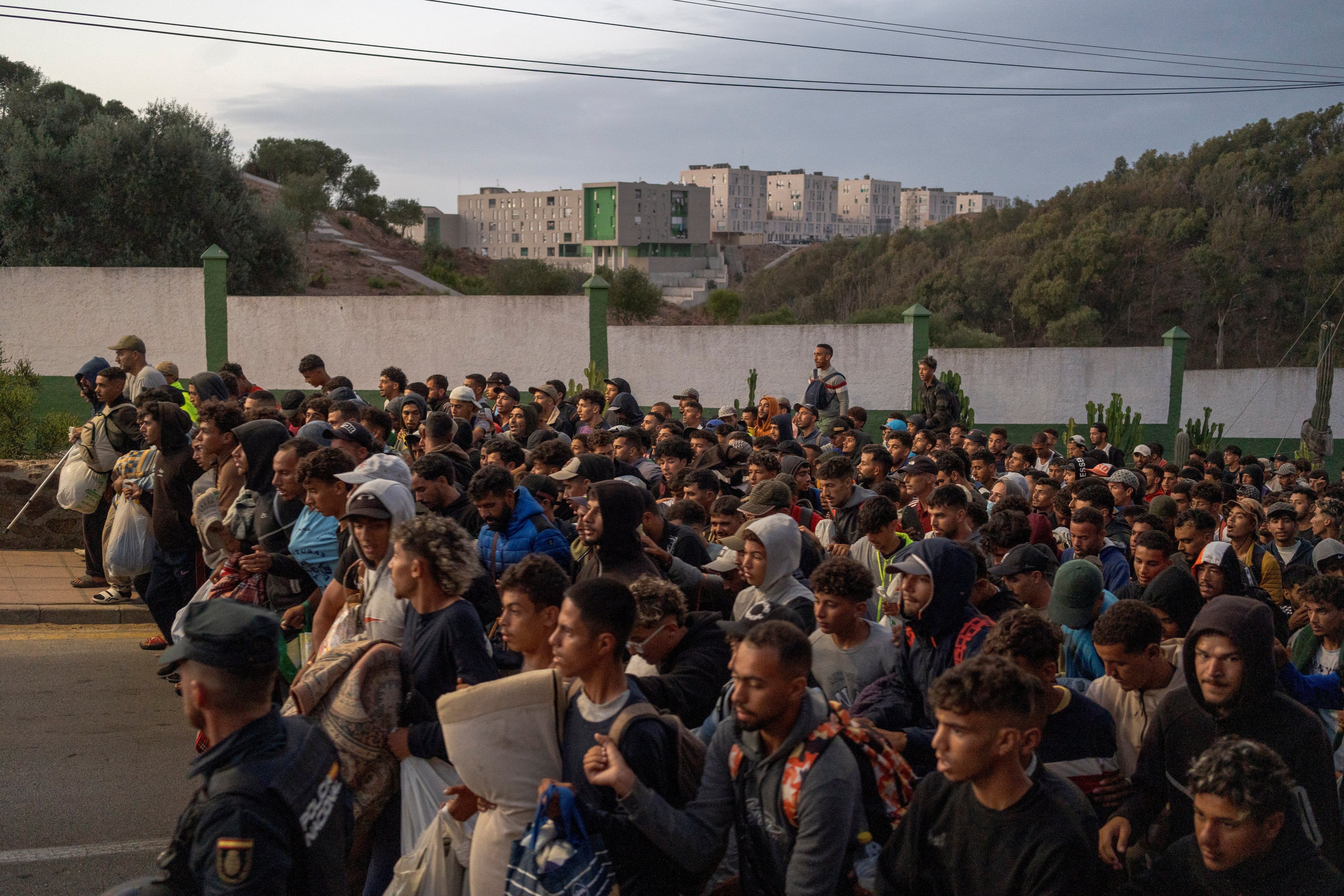 La policía controla a cientos de inmigrantes a su llegada a la nueva instalación.
