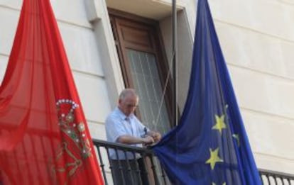 Un empleado municipal coloca a media asta las banderas del balcón del ayuntamiento.