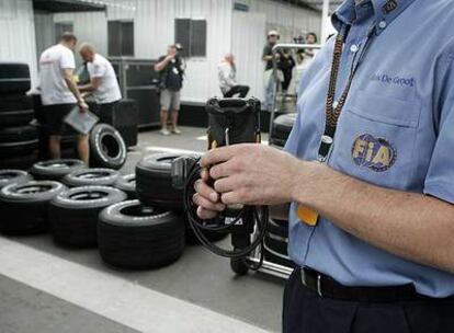 Un comisario de la FIA supervisa ayer la presión de los neumáticos cerca del <i>box</i> de McLaren.