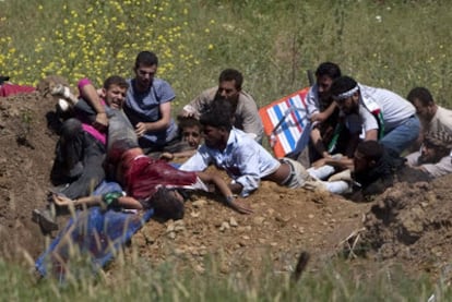 Un grupo de manifestantes propalestinos trata de ayudar a un compañero herido por disparos de soldados israelíes cuando trataban de cruzar la frontera desde Siria.
