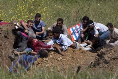 Un grupo de manifestantes propalestinos trata de ayudar a un compañero herido por disparos de soldados israelíes cuando trataban de cruzar la frontera desde Siria.