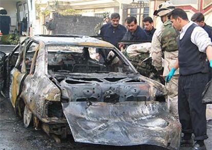 Agentes iraquíes y soldados de EE UU observan los restos de un vehículo calcinado tras los incidentes de Mosul.