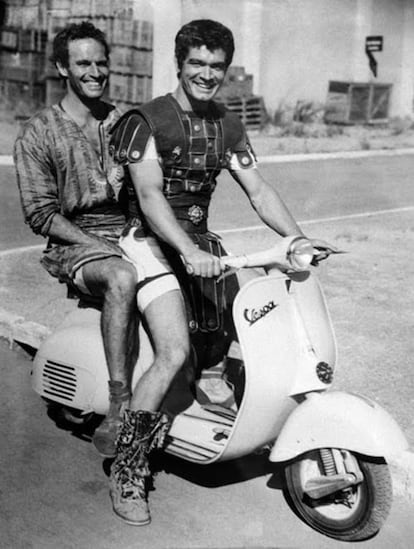 Amigos íntimos en tierras de Palestina, y ahora enemigos a muerte sobre la arena del circo romano, Charlton Heston y Stephen “Mesala” Boyd se relajan un rato en el plató de 'Ben-Hur' sobre una vespa antes de otra dura jornada de carrera de cuádrigas.