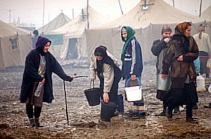 Mujeres chechenas toman agua potable de un surtidor en un campo de refugiados.