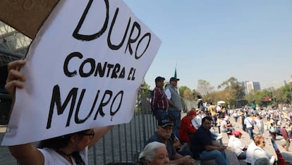 Una manifestante sostiene una pancarta contra Trump.