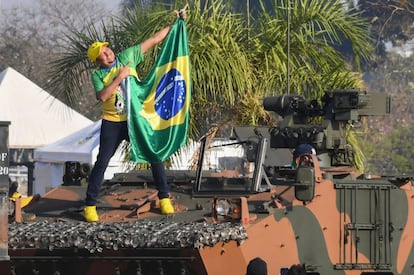 Un partidario del presidente brasileño sostiene una bandera desde un vehículo militar frente al palacio de la Alvorada, durante las celebraciones del Día de la Independencia en Brasilia.