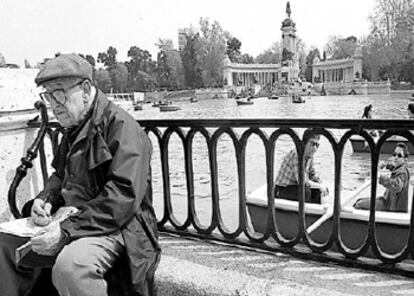 Un hombre hace un crucigrama junto al lago del Parque del Retiro