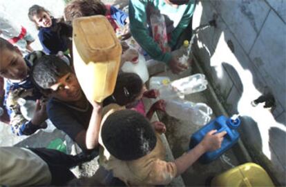 Un grupo de niños palestinos recogen agua en un campo de refugiados de Gaza.