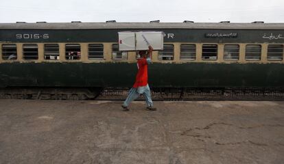 Un peón carga un frigorífico en la cabeza por el andén de la estación de Karachi (Pakistán). 14 de mayo de 2014.