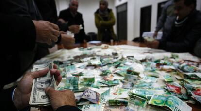 Ciudadanos palestinos recuentan el dinero recaudado en la campaña para reconstruir las casas de familiares de terroristas, el pasado 12 de enero.