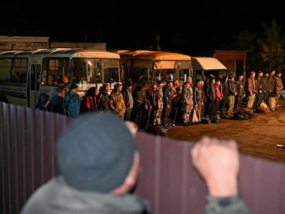 Un hombre observa a un grupo de reservistas reclutados en Rusia para la guerra de Ucrania.