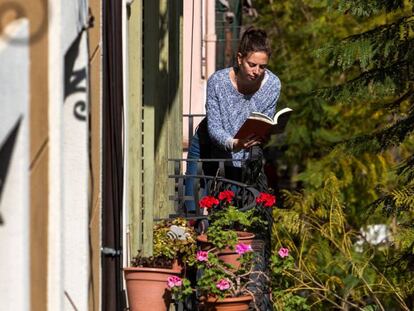 Una mujer lee un libro en el balcón de su casa, durante el confinamiento en Barcelona.