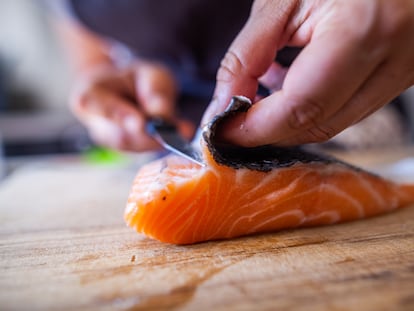 Un cocinero quita la piel a un lomo de salmón.