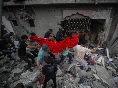 Un grupo de palestinos recuperan los restos de una mujer entre los escombros de una casa destruida tras un ataque aéreo israelí en el campo de refugiados de Al Nusairat, sur de la Franja de Gaza, 27 de abril de 2024.