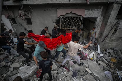 Un grupo de palestinos recuperan los restos de una mujer entre los escombros de una casa destruida tras un ataque aéreo israelí en el campo de refugiados de Al Nusairat, sur de la Franja de Gaza, 27 de abril de 2024.