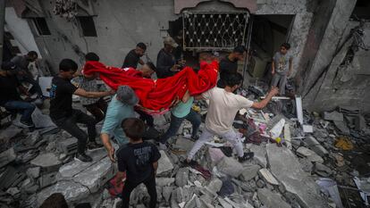 Un grupo de palestinos recuperan los restos de una mujer entre los escombros de una casa destruida tras un ataque aéreo israelí en el campo de refugiados de Al Nusairat, sur de la Franja de Gaza, 27 de abril de 2024.