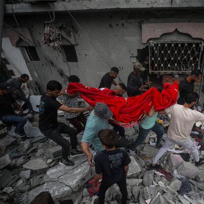 Un grupo de palestinos recuperan los restos de una mujer entre los escombros de una casa destruida tras un ataque aéreo israelí en el campo de refugiados de Al Nusairat, sur de la Franja de Gaza, 27 de abril de 2024.