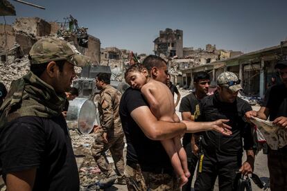 Homem carrega criança nos braços para sair da última zona controlada pelo Estado Islâmico na Cidade Velha de Mosul, no Iraquel, em 12 de julho de 2017. Fotografia indicada na categoria 'Photo of the Year' do fotógrafo Ivor Prickett.