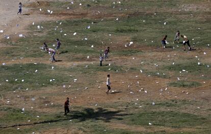 Vários palestinos recolhem folhetos jogados por um avião israelense no bairro de Rimal, em Gaza.