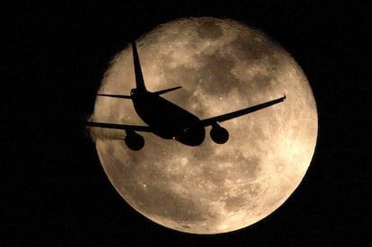 Un avión cruza por delante de la luna llena en Málaga.