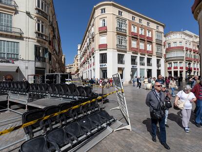 Varias personas caminan junto a las tribunas que se están montando para la próxima Semana Santa en Málaga, este jueves.