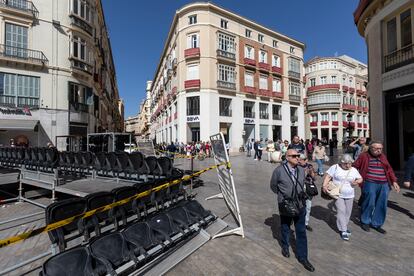 Varias personas caminan junto a las tribunas que se están montando para la próxima Semana Santa en Málaga, este jueves.