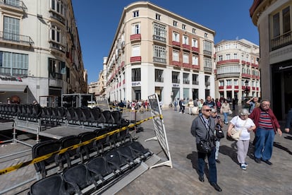 Varias personas caminan junto a las tribunas que se están montando para la próxima Semana Santa en Málaga, este jueves.