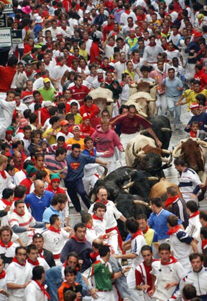 Pamplona, 11 de julio de 2004. Numerosos mozos corren entre las reses de la ganadería sevillana de Miura, en mitad de la calle de Estafeta, durante el quinto encierro de los sanfermines.
