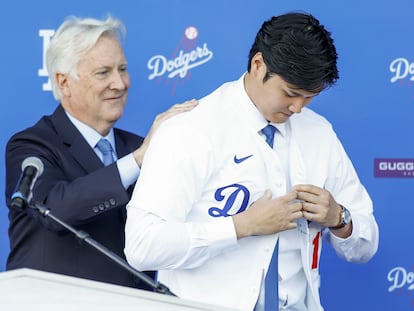 Mark Walter, uno de los dueños de los Dodgers, ayuda a Ohtani a ponerse la camiseta del equipo de Los Ángeles.