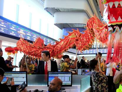 Operadores observan el desfile de un dragón tradicional en la Bolsa de Manila (Filipinas)