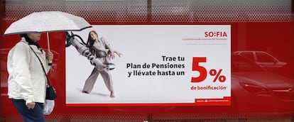 Una mujer pasa delante de un cartel promocionando planes de pensiones.